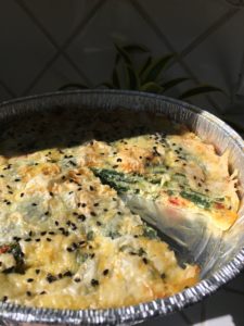 A close up a sun drenched tin pan of Zelnik Pie with one piece of pie missing