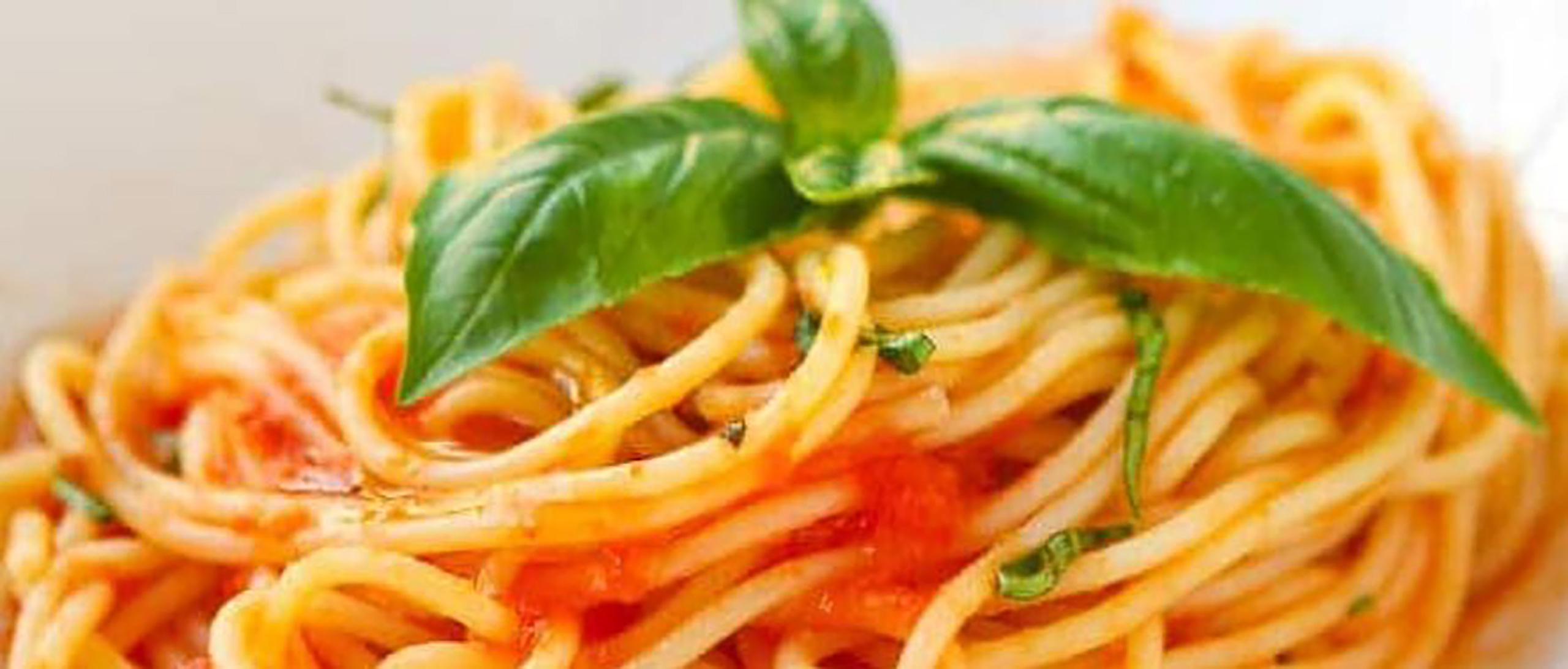 A bowl of thick homemade spaghetti with tomatoes diced medium fine and freshly picked basil leaves