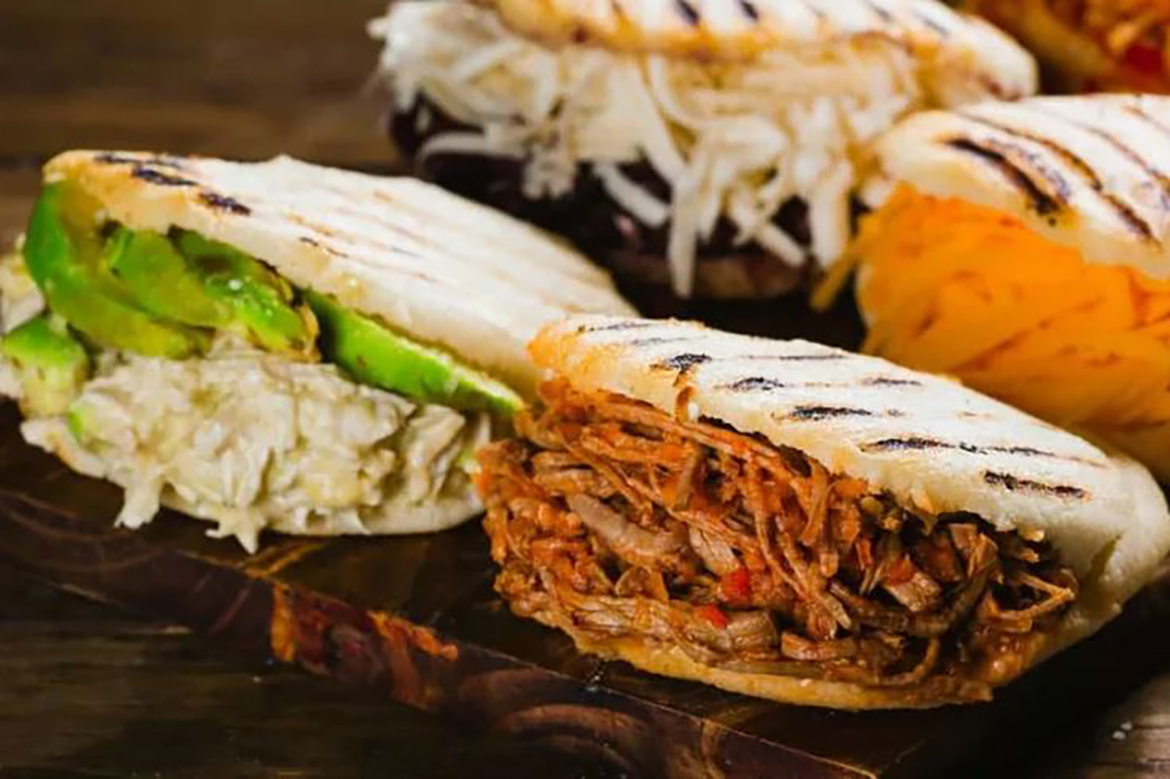 Four grilled flat, round, unleavened pieces of dough called Arepas, each cut and stuffed with different ingredients