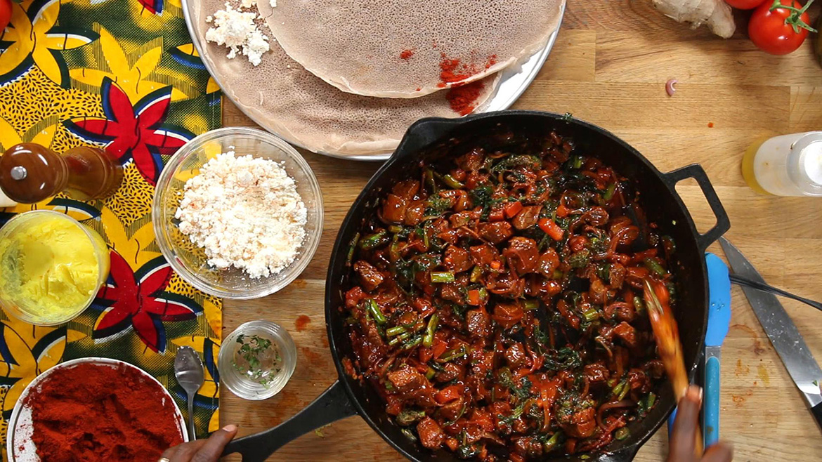 Unseen Chef Marcus Samuelsson stirs beef tenderloin, broccoli, and tomatoes in a cast iron pan for the Ethiopian dish Tibs